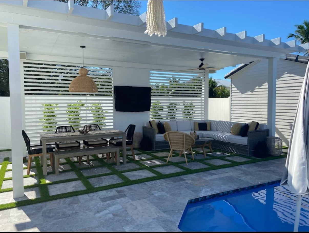 Covered outdoor living area with geometric pavers and turf