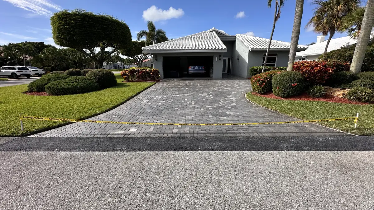 Compacted asphalt repair band beside a Boynton Beach paver driveway
