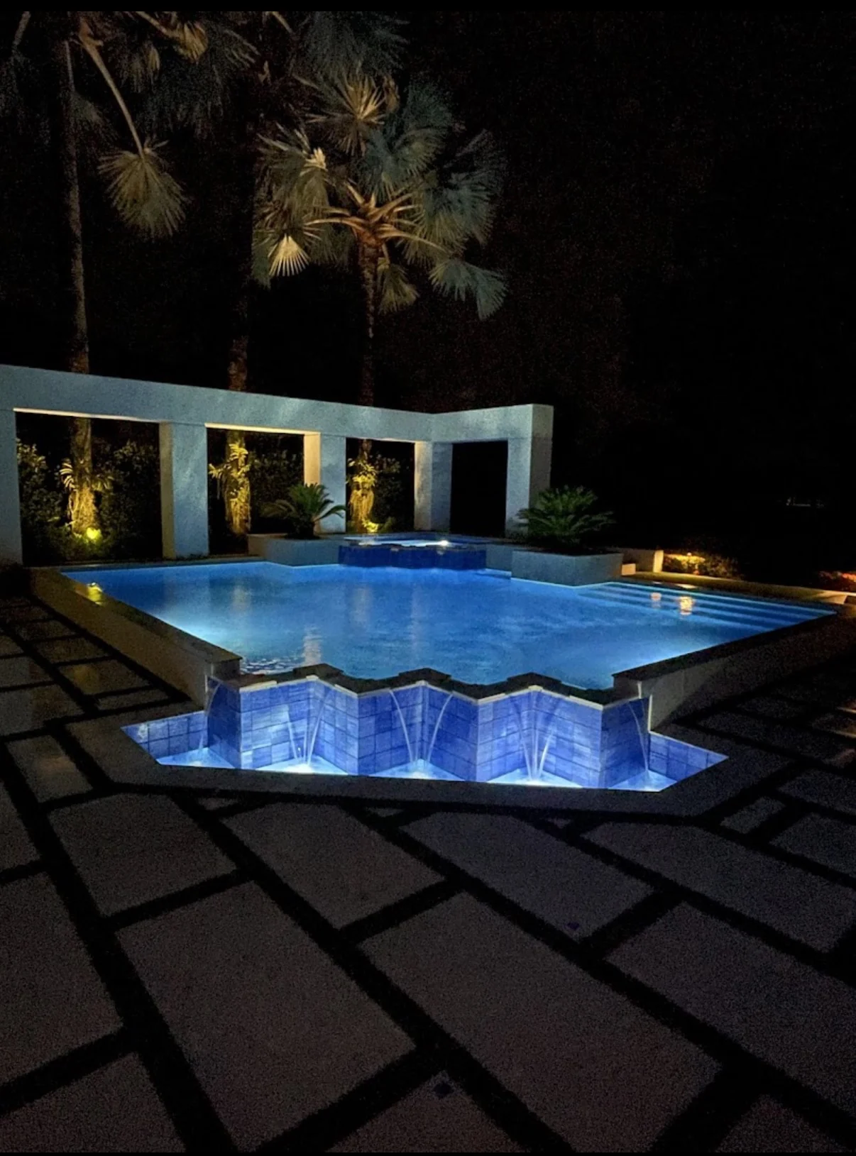 Completed illuminated pool and paver-turf backyard at night