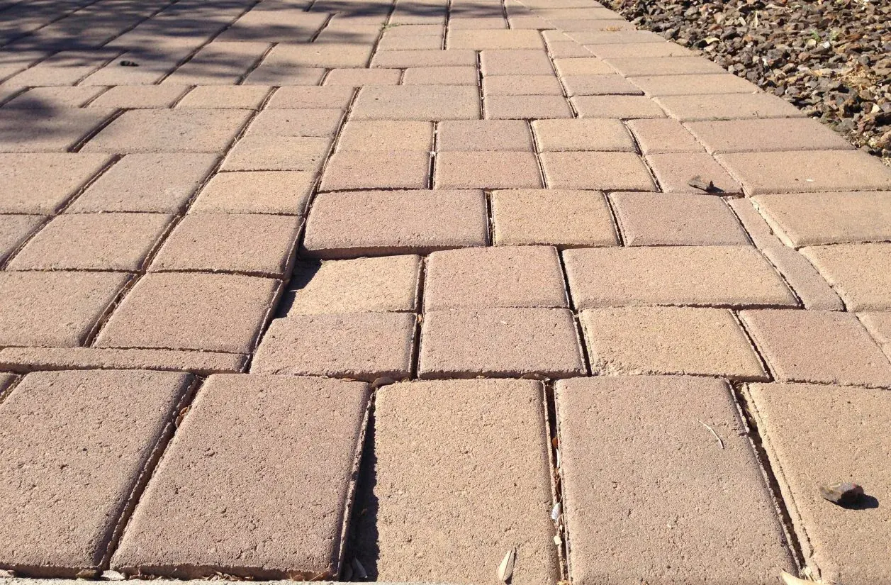 Uneven driveway pavers creating a visible trip hazard before repair